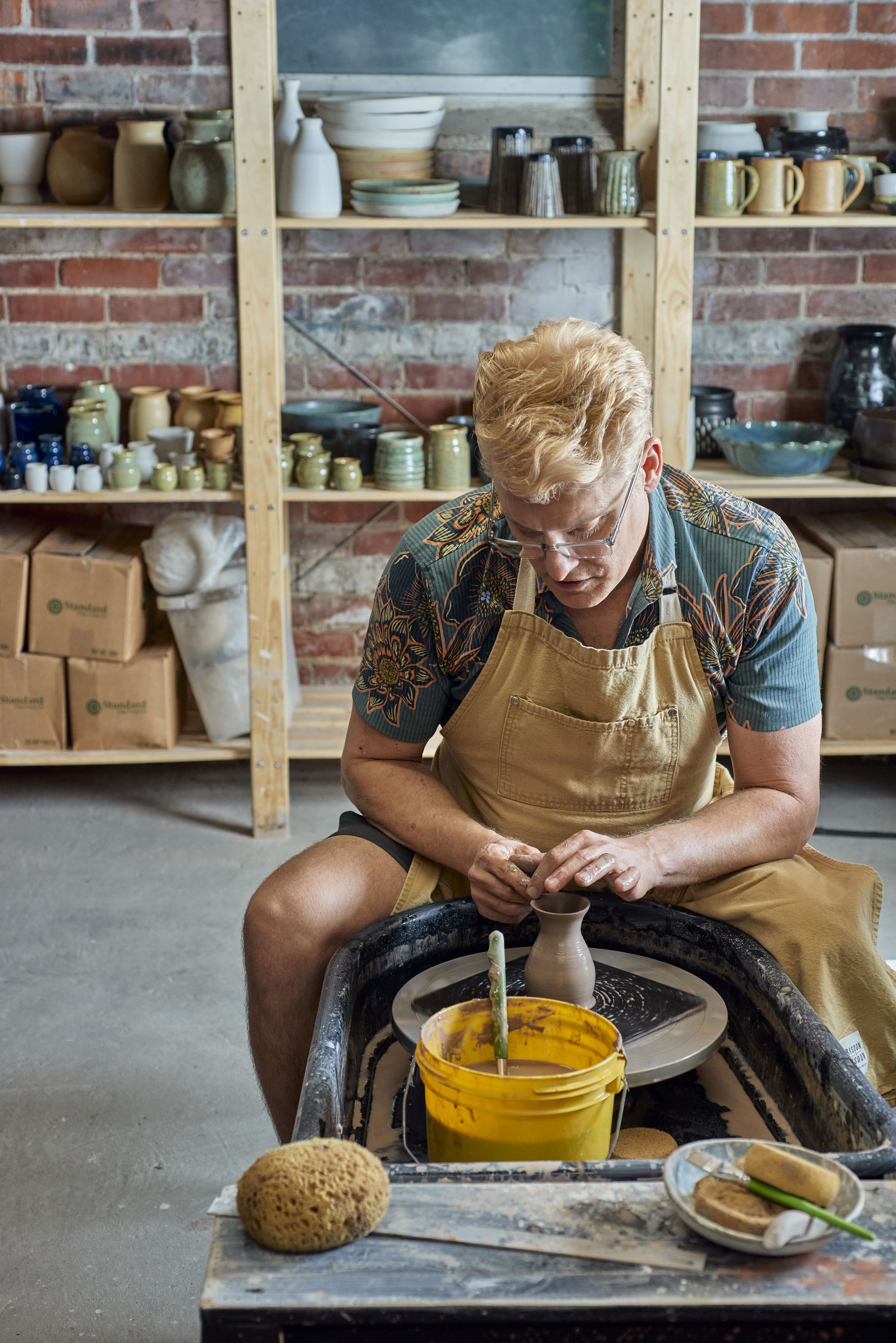 Brian working with clay on a pottery wheel in a studio setting