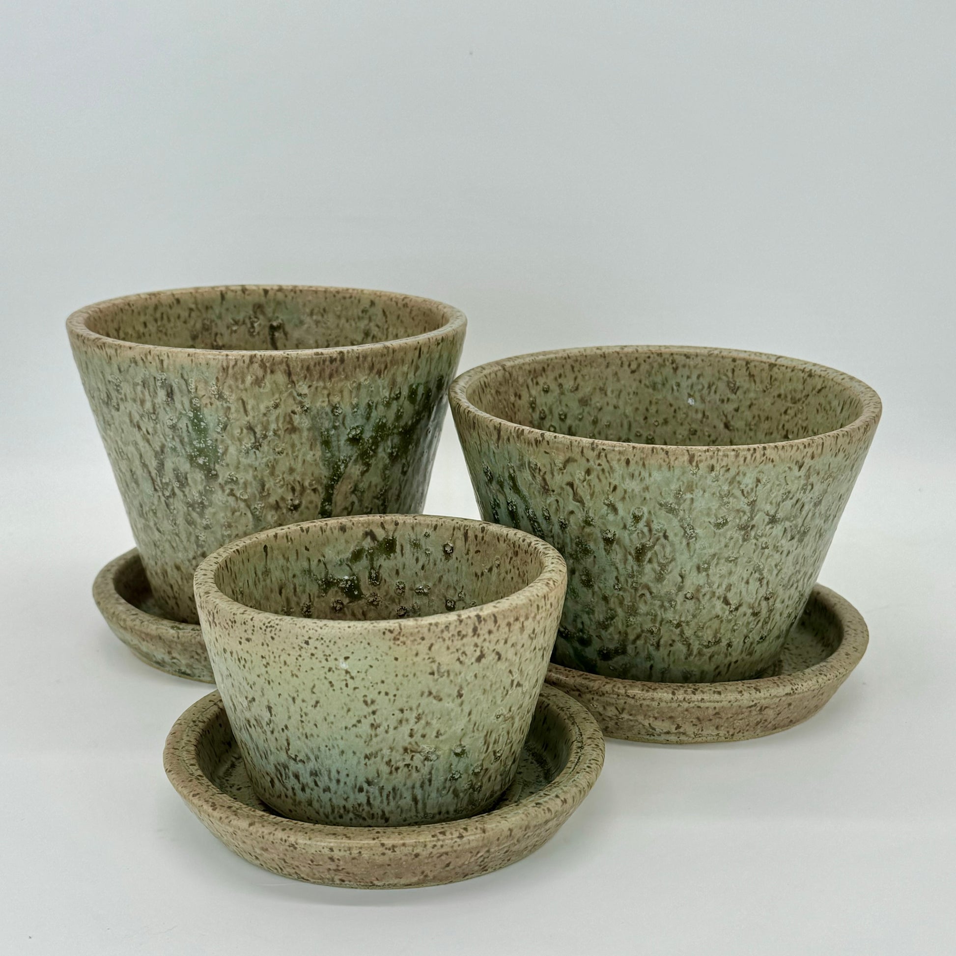 Set of three hand-crafted flower pot and plate in pale seaweed green inspired by Long Island Sound in New York. Ceramic planter features drainage hole and plate.