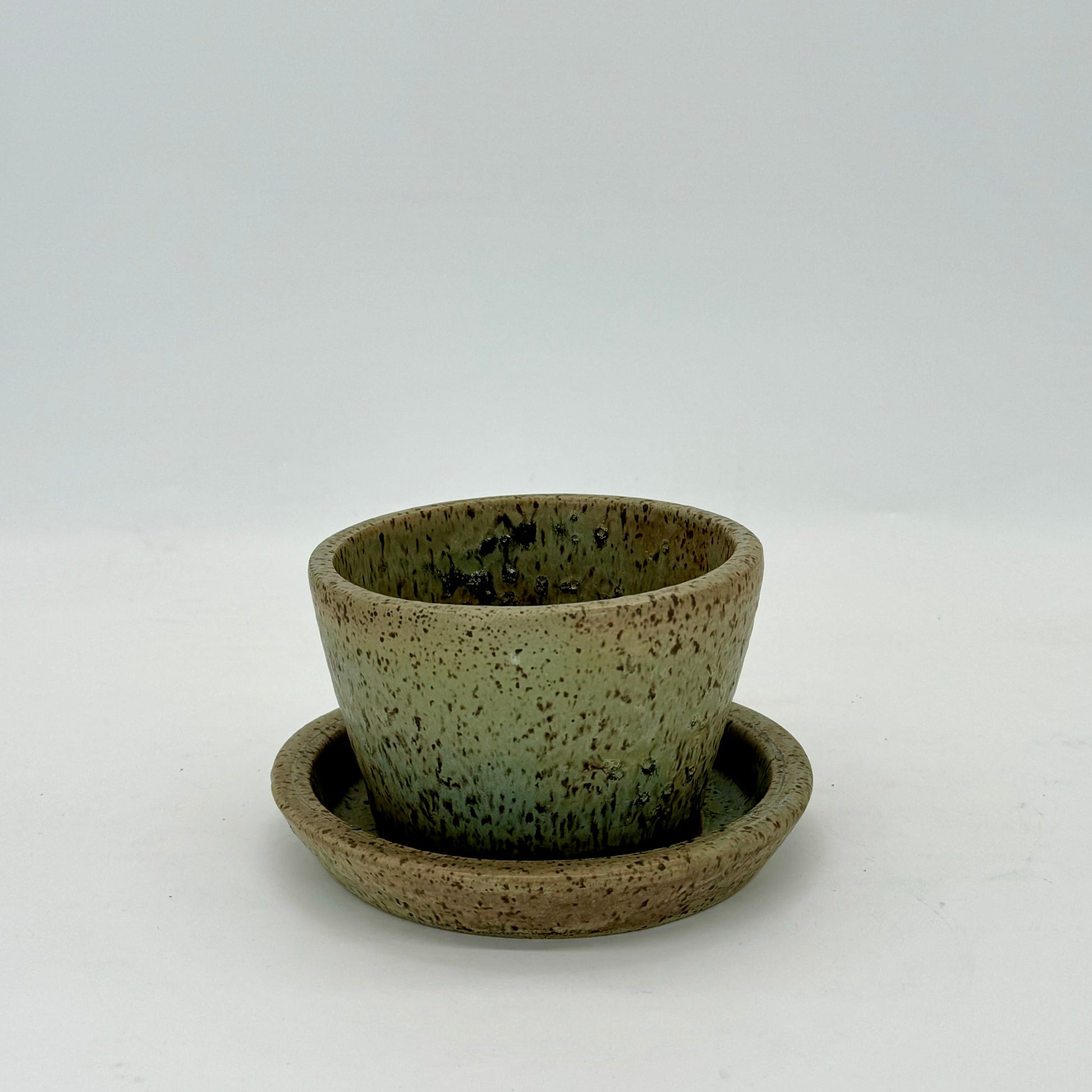 Small hand-crafted flower pot and plate in pale seaweed green inspired by Long Island Sound in New York. Ceramic planter features drainage hole and plate.