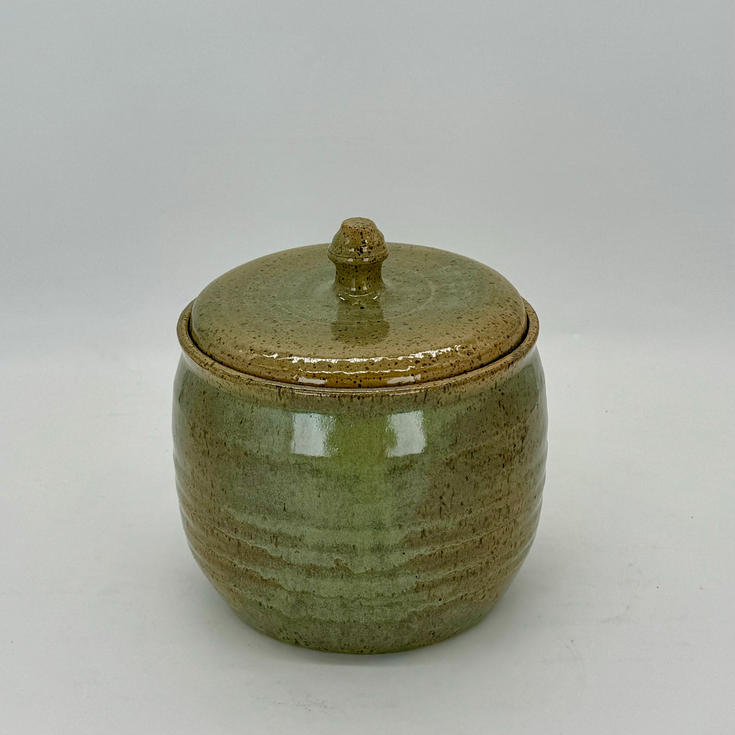 Speckled green treat jar with subtle rings around the vessel. Sea mist inspired glazed.