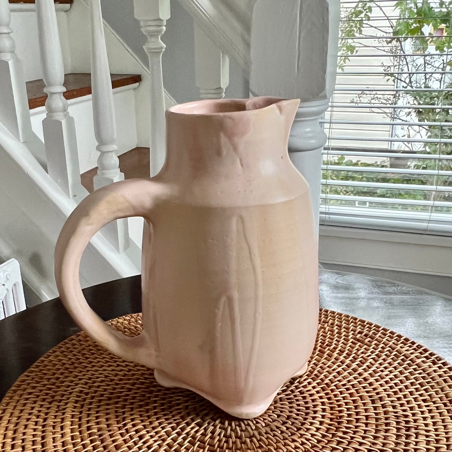 Four-footed pink pitcher. Pitcher set on table.