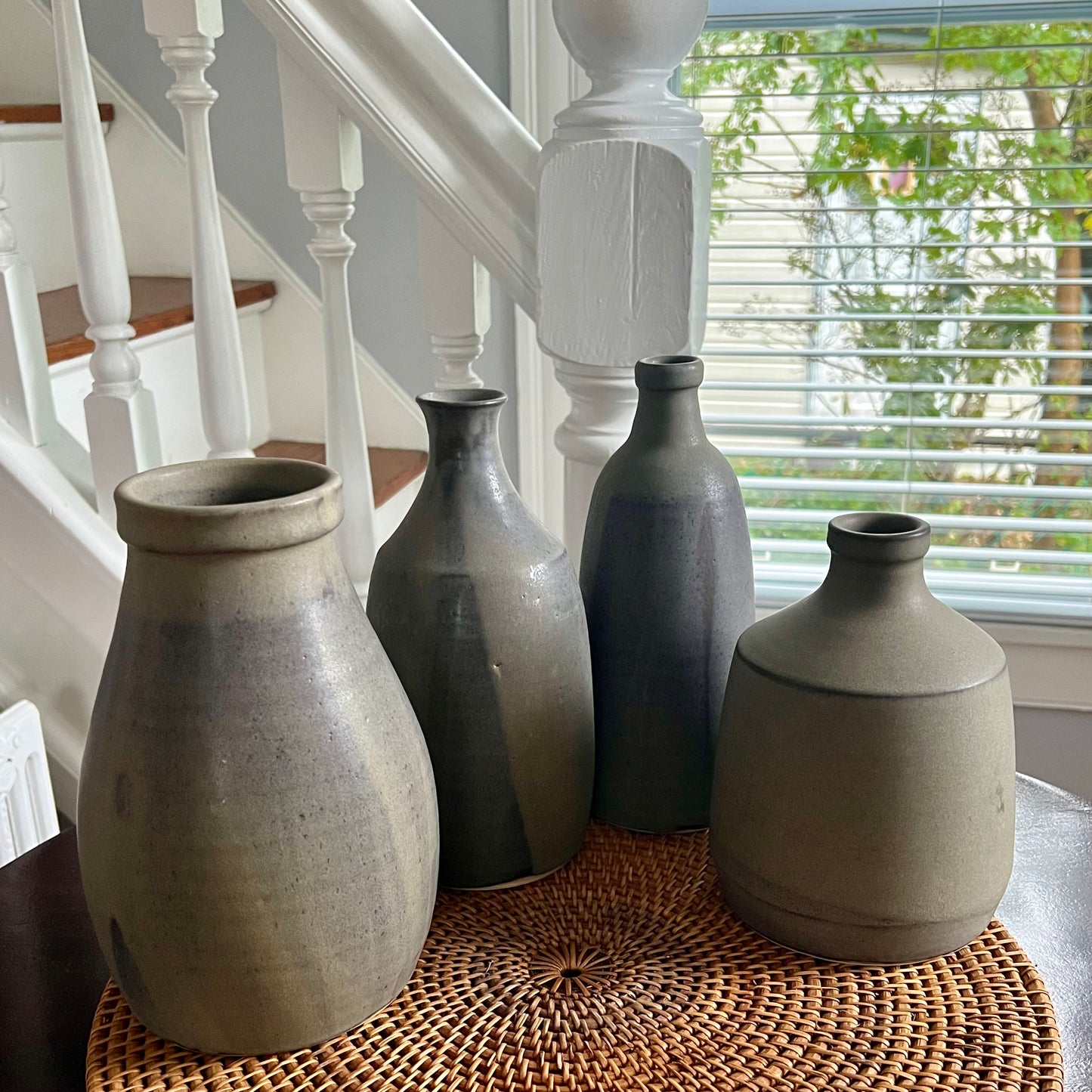 Sturdy, rotund vase with a strong lip. Finished in pour-over pussywillow (brown/gray matte glaze). Image of four vases of different shapes and sizes set on table.