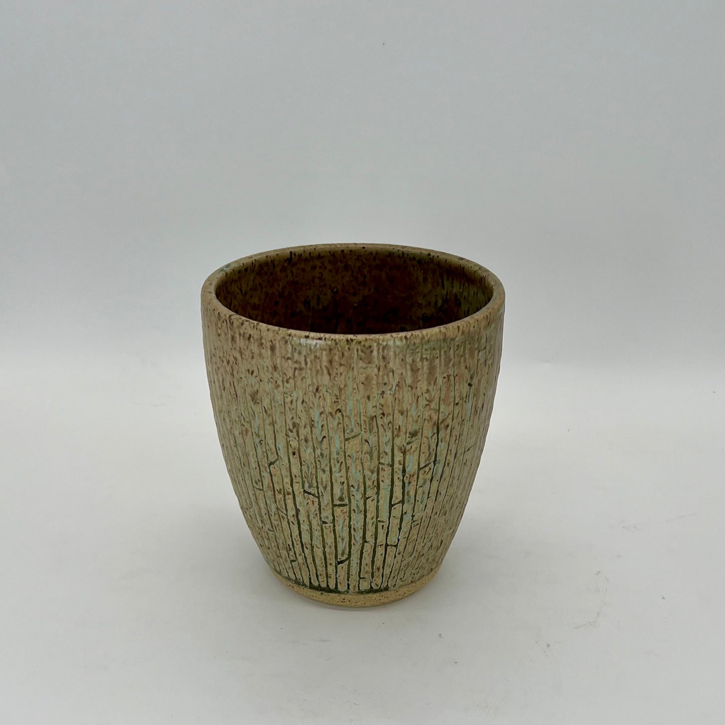Vase with seaweed glaze and carved pieces creating crevices within the vessel. Pattern evokes bamboo.