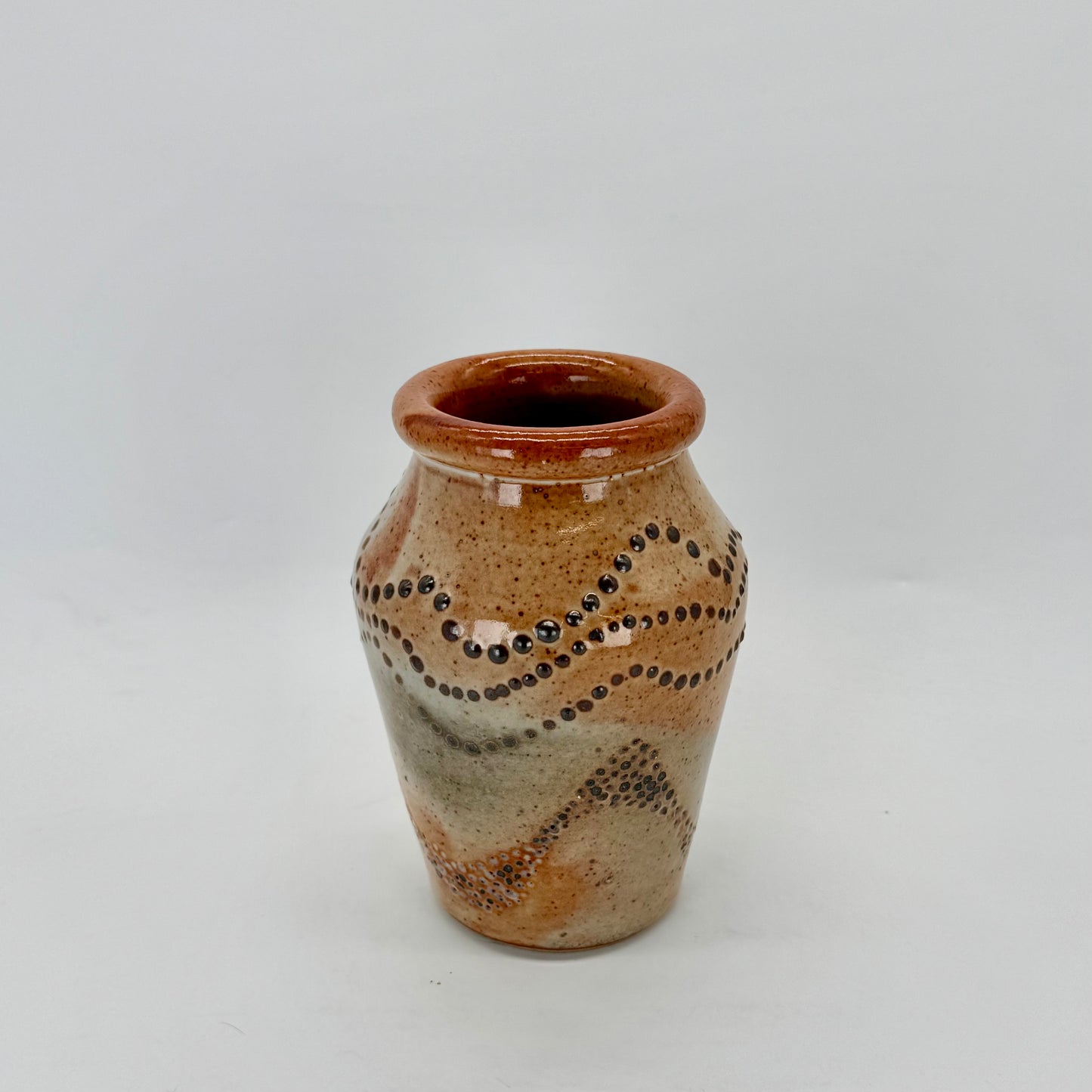 Small vase with experimental surface design — pressed dimples using an acorn and slip trailing using dots of black slip. Glazed in glossy shino glaze.