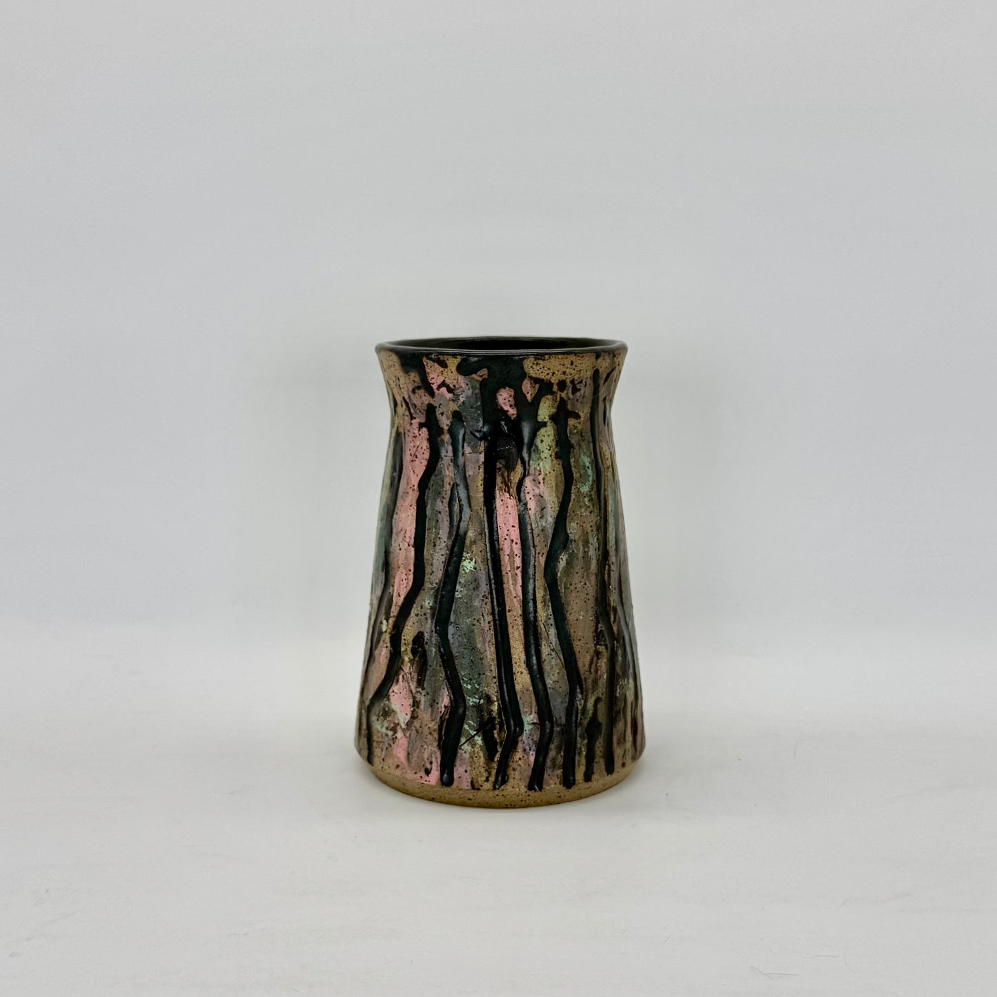 Colorful and carved vase with surface decoration techniques — underglaze transfer of teal, yellow and mahogany, carving, wax resist over the color and glazing the negative space in satin charcoal