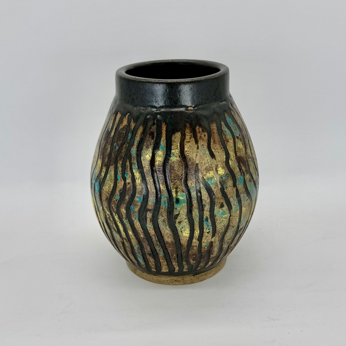 Large colorful and carved vase with surface decoration techniques — underglaze transfer of teal, yellow and mahogany, carving, wax resist over the color and glazing the negative space in satin charcoal