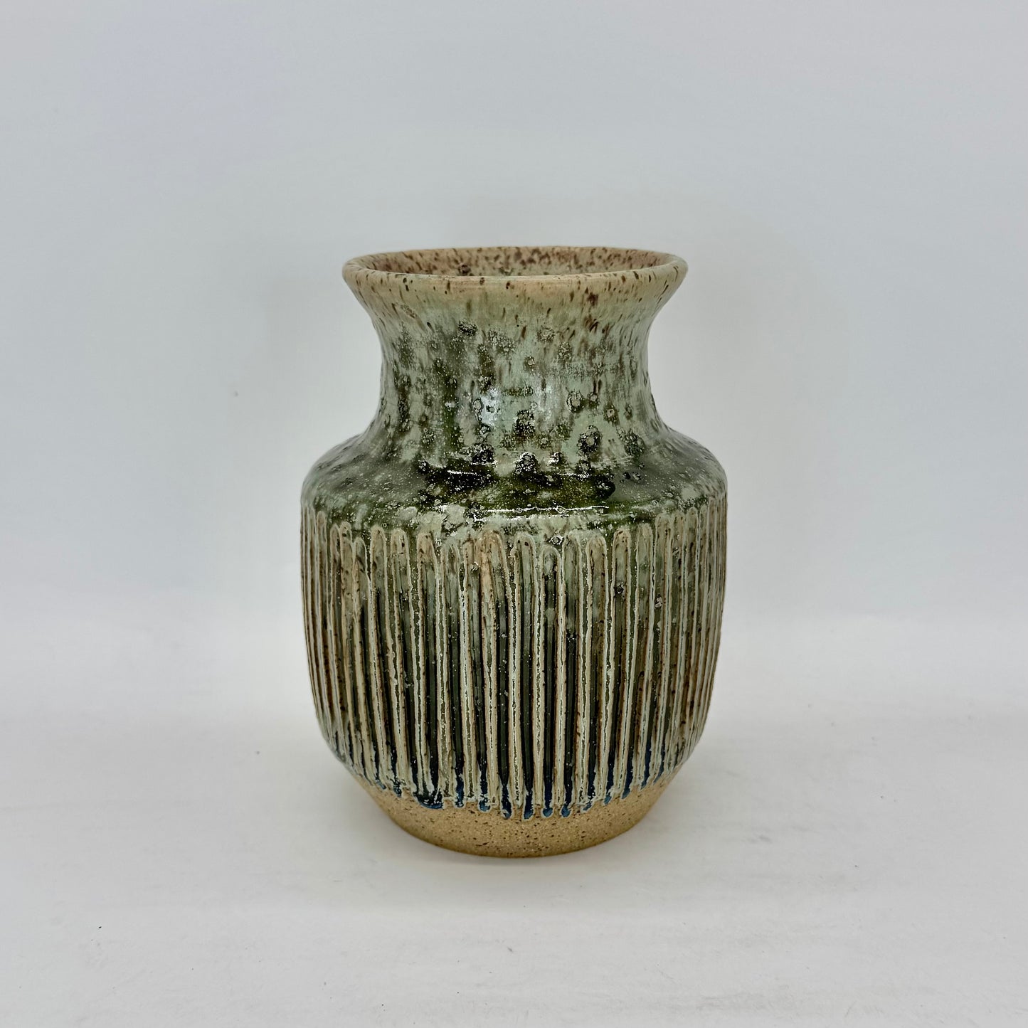 Green ceramic vase with ribbed texture on a white background