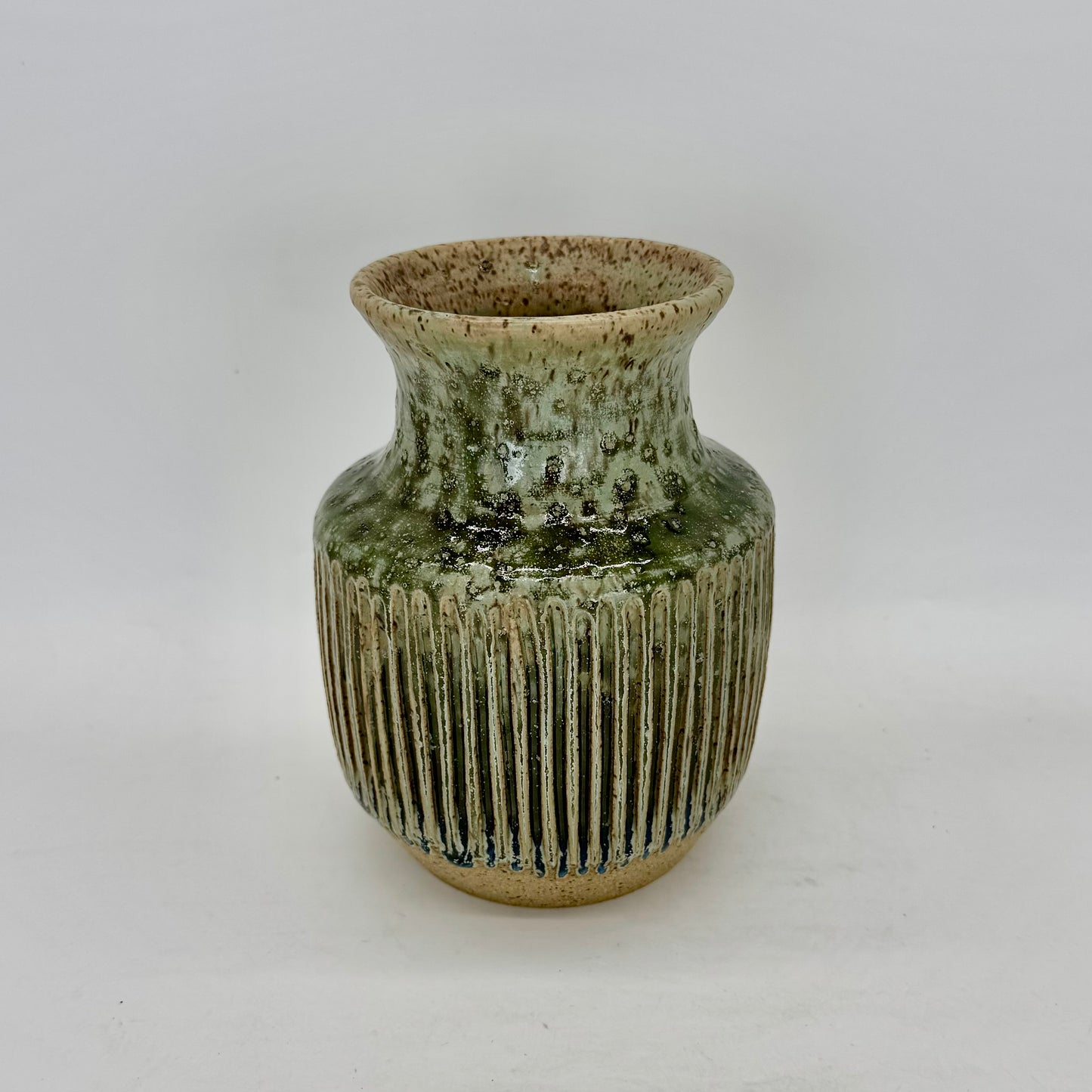 With a silhouette inspired by classic Art Deco design, this vase features tight, elegant fluting that enhances the flow of its pale seaweed green glaze. The carved ridges invite the glaze to pool and deepen, revealing subtle tonal shifts and at the base of the fluting, a surprising transformation into a deep blue, adding depth and intrigue to the form. Brian Burgess Ceramics makes handcrafted stoneware ceramics on the North Fork of Long Island, New York, for the garden, home and table. Buy local. Support sm