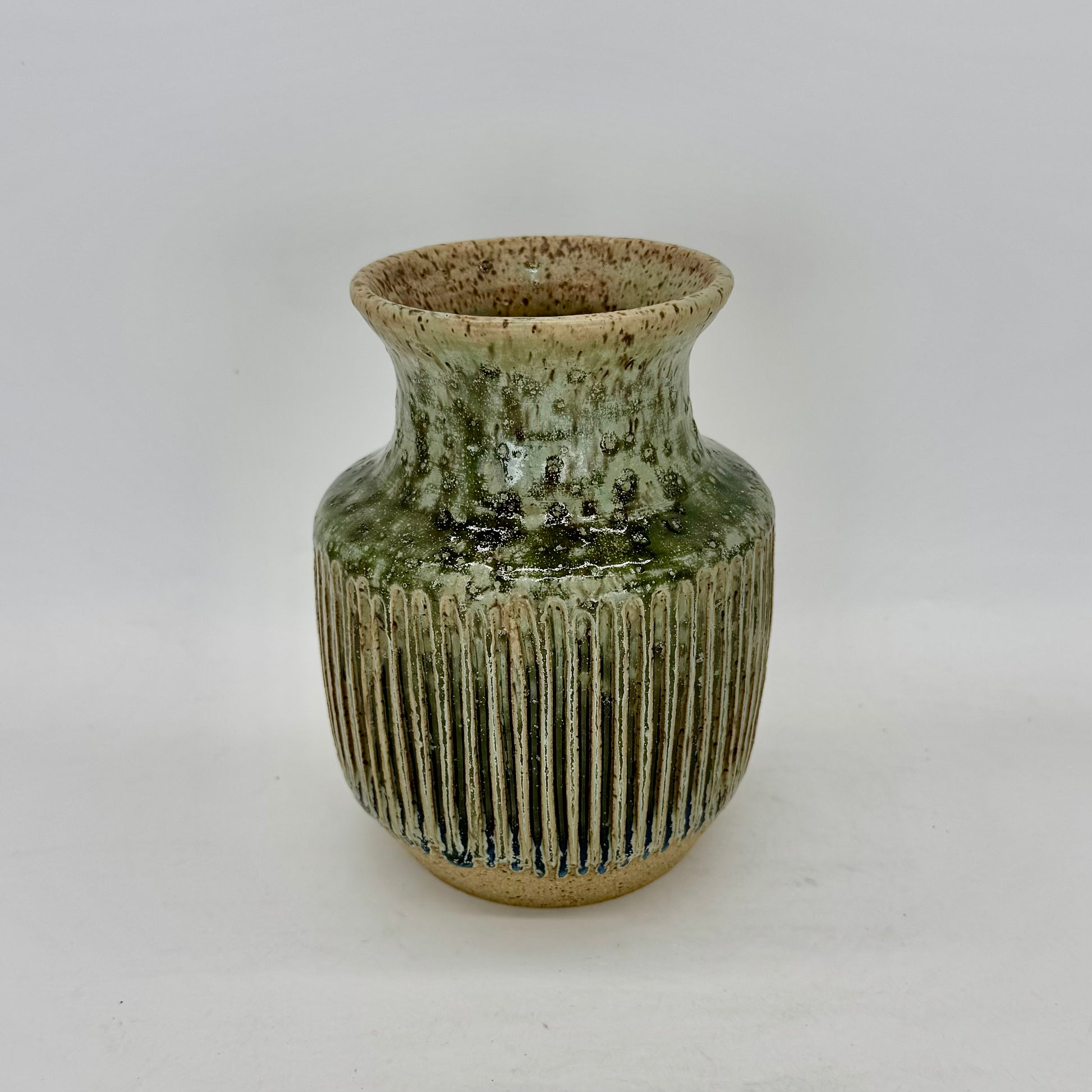 With a silhouette inspired by classic Art Deco design, this vase features tight, elegant fluting that enhances the flow of its pale seaweed green glaze. The carved ridges invite the glaze to pool and deepen, revealing subtle tonal shifts and at the base of the fluting, a surprising transformation into a deep blue, adding depth and intrigue to the form. Brian Burgess Ceramics makes handcrafted stoneware ceramics on the North Fork of Long Island, New York, for the garden, home and table. Buy local. Support sm