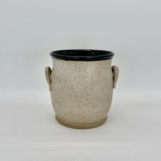 This vessel doubles beautifully as a sculptural accent or functional vase. It features two charming lug handles and a glossy black interior that contrasts elegantly with its soft, matte transparent exterior glaze. The finish subtly reveals the natural speckling of the clay body, adding depth and organic texture to its minimalist form. Brian Burgess Ceramics makes handcrafted stoneware ceramics on the North Fork of Long Island, New York, for the garden, home and table. Buy local. Support small businesses.