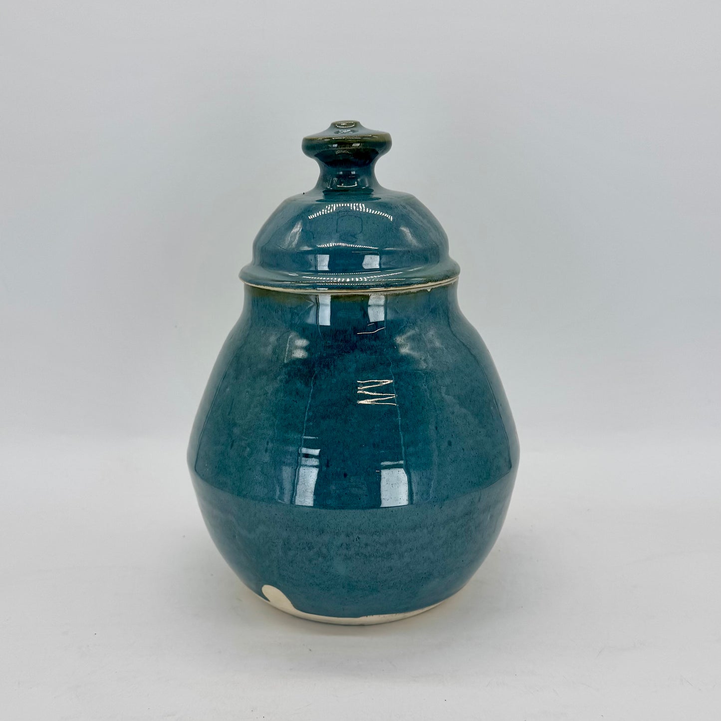This rotund cookie jar features a geometric base and a substantial lid topped with a bold, easy-to-grip knob. Finished in a glossy blue-green glaze that feels both dreamy and ethereal, it’s a charming addition to any kitchen. Perfect for cookies, snacks or pet treats. Brian Burgess Ceramics makes handcrafted stoneware ceramics on the North Fork of Long Island, New York, for the garden, home and table. Buy local. Support small businesses. Handmade. Small batch. 