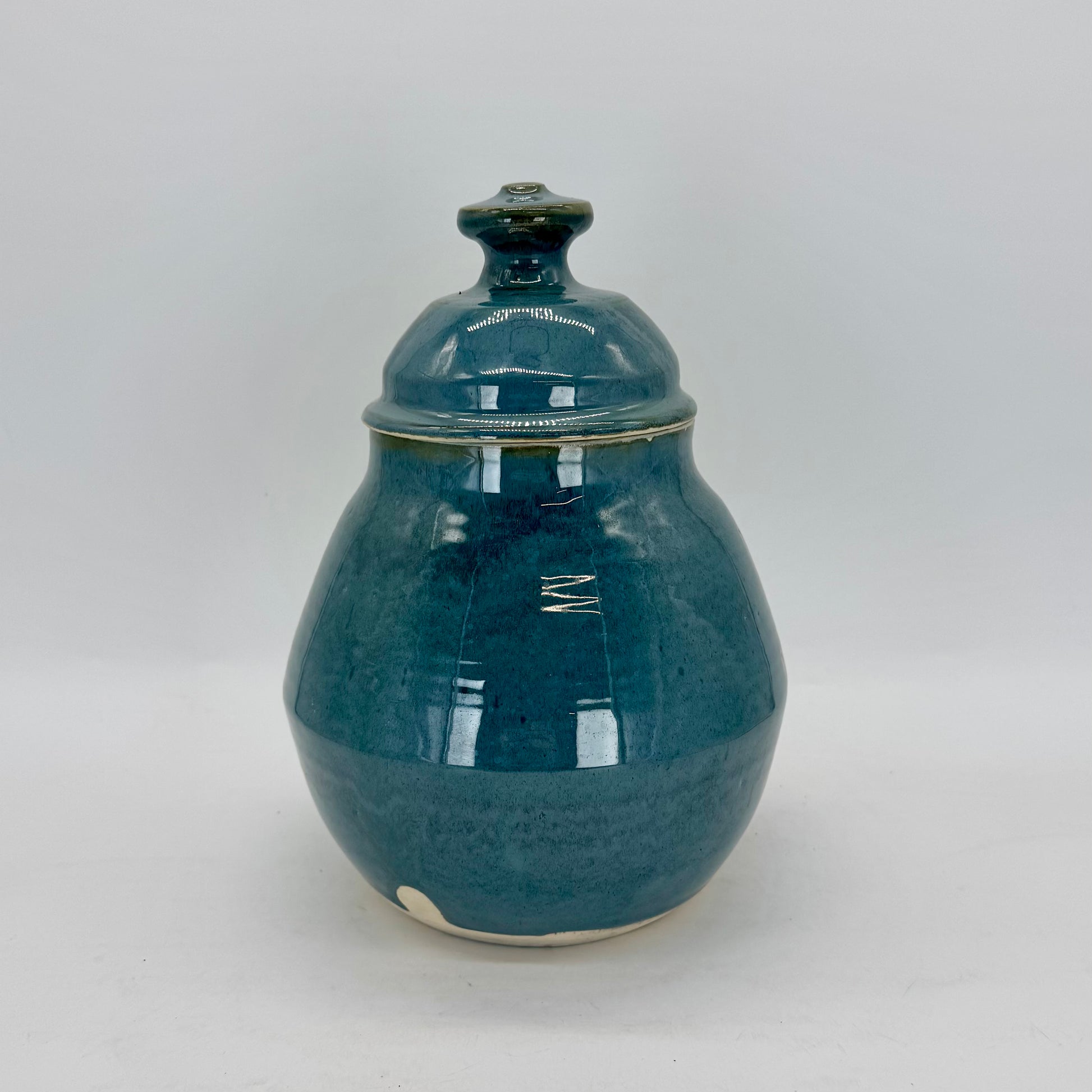 This rotund cookie jar features a geometric base and a substantial lid topped with a bold, easy-to-grip knob. Finished in a glossy blue-green glaze that feels both dreamy and ethereal, it’s a charming addition to any kitchen. Perfect for cookies, snacks or pet treats. Brian Burgess Ceramics makes handcrafted stoneware ceramics on the North Fork of Long Island, New York, for the garden, home and table. Buy local. Support small businesses. Handmade. Small batch. 