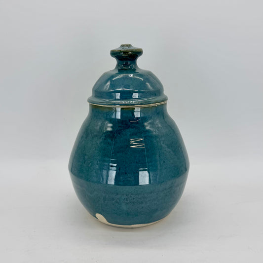 This rotund cookie jar features a geometric base and a substantial lid topped with a bold, easy-to-grip knob. Finished in a glossy blue-green glaze that feels both dreamy and ethereal, it’s a charming addition to any kitchen. Perfect for cookies, snacks or pet treats. Brian Burgess Ceramics makes handcrafted stoneware ceramics on the North Fork of Long Island, New York, for the garden, home and table. Buy local. Support small businesses. Handmade. Small batch. 