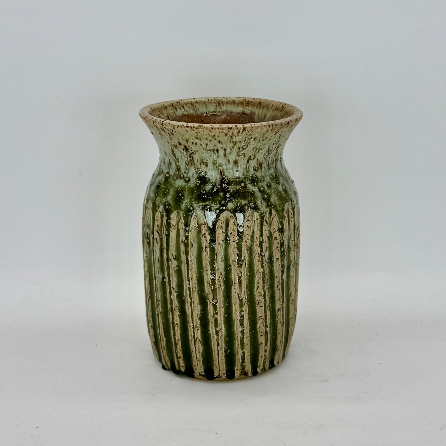 This classic-shaped vase features fluting that highlights the beauty of its pale seaweed green glaze. The carved details allow the glaze to pool and deepen, creating subtle variations in tone and texture that add depth and visual interest. Brian Burgess Ceramics makes handcrafted stoneware ceramics on the North Fork of Long Island, New York, for the garden, home and table. Buy local. Support small businesses. Handmade. Small batch. 
