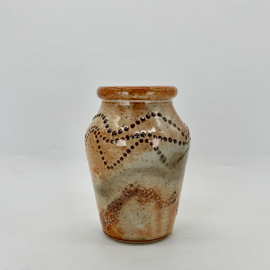 Small vase with experimental surface design — pressed dimples using an acorn and slip trailing using dots of black slip. Glazed in glossy shino glaze.