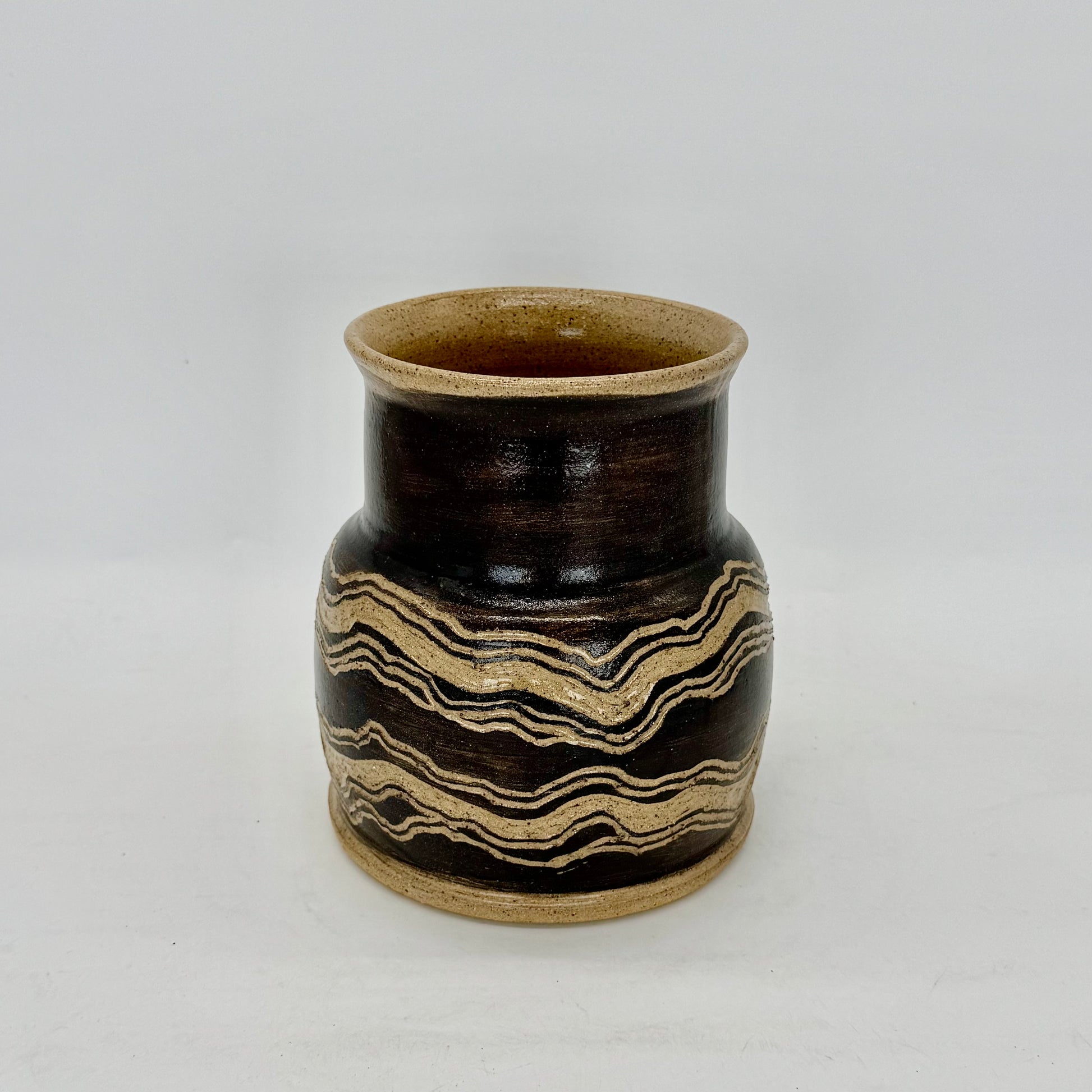 Hand-painted in black terra sigillata slip and intricately carved, this vessel draws inspiration from the layered sedimentary rocks scattered along the beaches of the North Fork. A tribute to the Earth’s enduring beauty, strength, and resilience, it’s finished in a clear, transparent glaze that enhances the depth and texture of each carved line. Brian Burgess Ceramics makes handcrafted stoneware ceramics on the North Fork of Long Island, New York, for the garden, home and table. Buy local. 