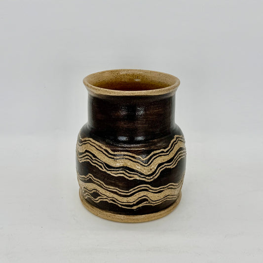 Hand-painted in black terra sigillata slip and intricately carved, this vessel draws inspiration from the layered sedimentary rocks scattered along the beaches of the North Fork. A tribute to the Earth’s enduring beauty, strength, and resilience, it’s finished in a clear, transparent glaze that enhances the depth and texture of each carved line. Brian Burgess Ceramics makes handcrafted stoneware ceramics on the North Fork of Long Island, New York, for the garden, home and table. Buy local. 