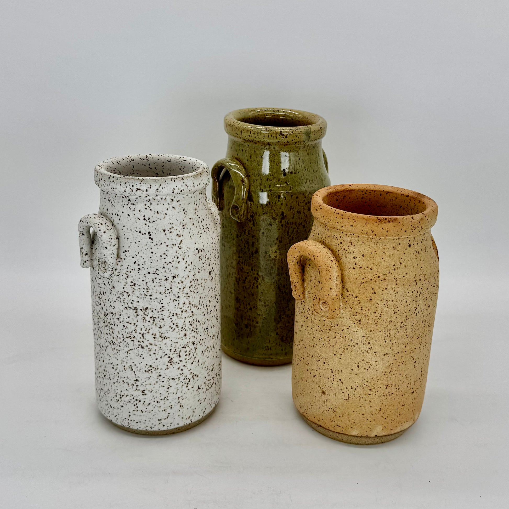 Set of three Classic milk bottle shaped vessel that works as a vase or decorative vessels for the modern farmhouse. Each vase features charming lug handles, and finished in matte white, speckled farm egg and serene sea mist glazes. Brian Burgess Ceramics makes handcrafted stoneware ceramics on the North Fork of Long Island, New York, for the garden, home and table. Buy local. Support small businesses. Handmade. Small batch. 