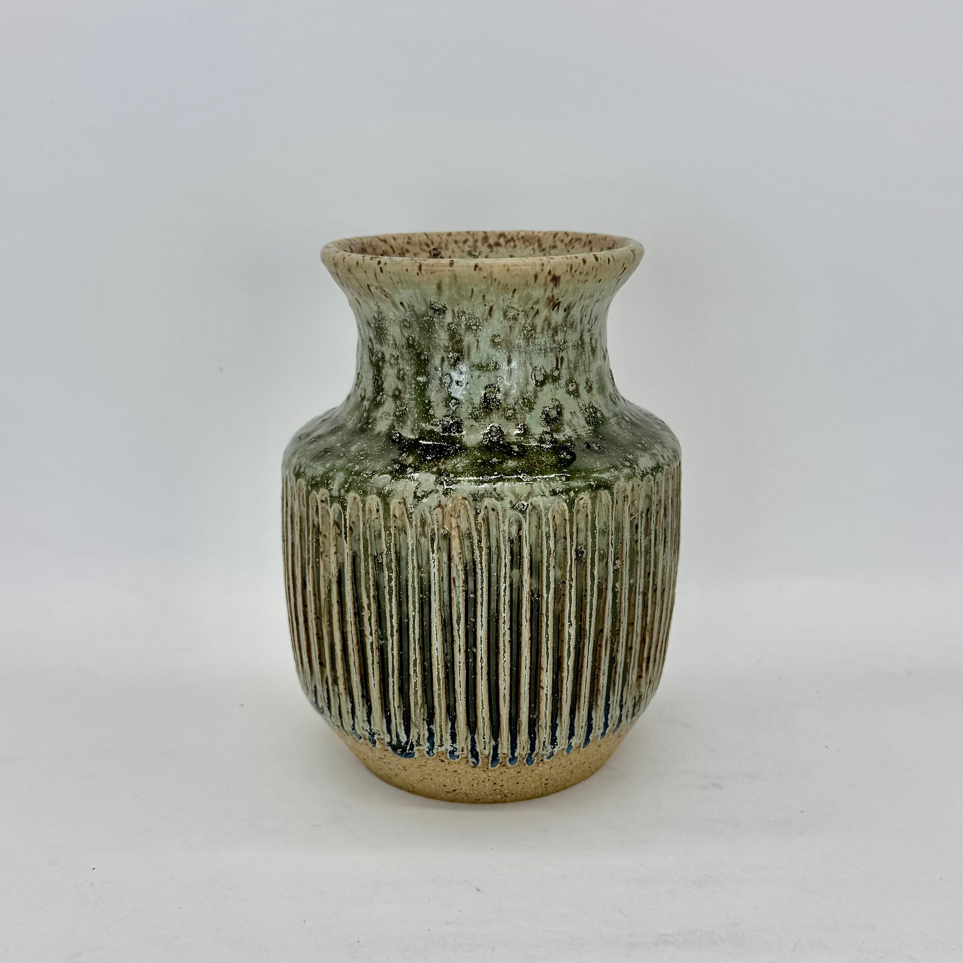 Green ceramic vase with ribbed texture on a white background