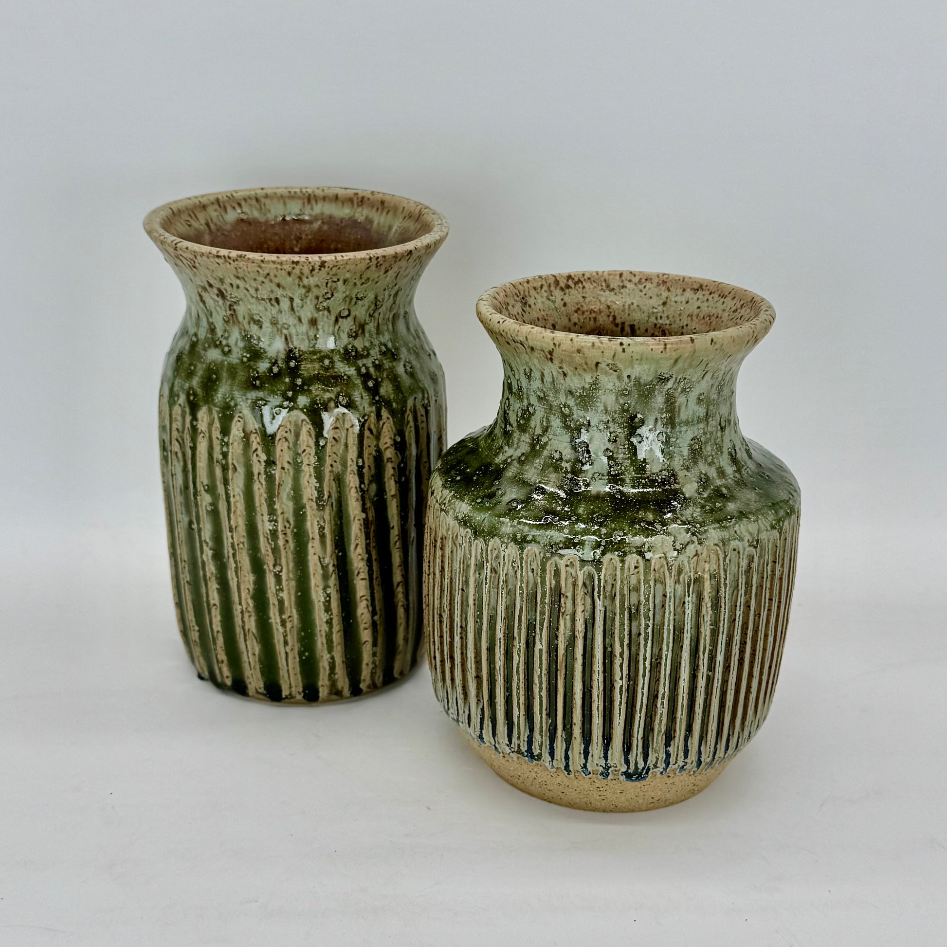 Two ceramic vases with green and brown glaze on a white background