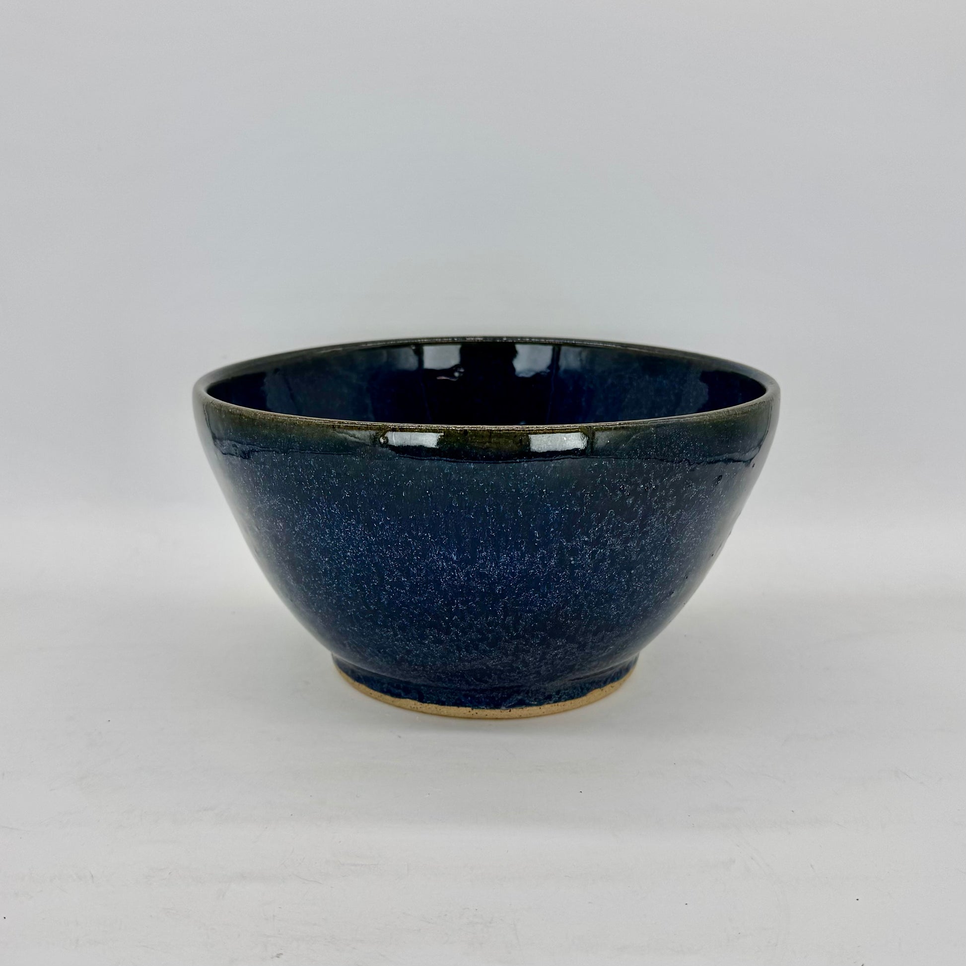 Crafted on the wheel from speckled brown clay and finished in a rich, moody blue glaze, this serving bowl blends rustic character with coastal charm. Its deep hue makes a striking backdrop for colorful dishes like fluffy rice, roasted potatoes, or crisp green beans, bringing depth and contrast to your table with every meal. Brian Burgess Ceramics makes handcrafted stoneware ceramics on the North Fork of Long Island, New York, for the garden, home and table. Buy local. Support small businesses. Handmade.